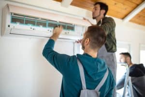 Repairman team installing air conditioner at client's home